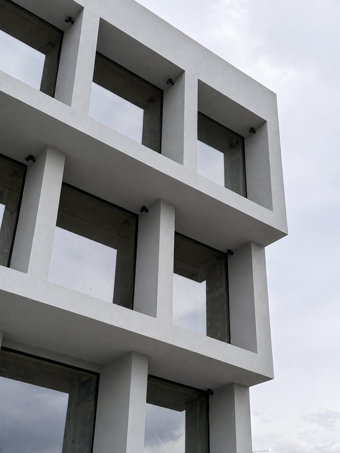Minimal aluminium façade featuring large glazed openings and slim frame windows at the MOB1 project.