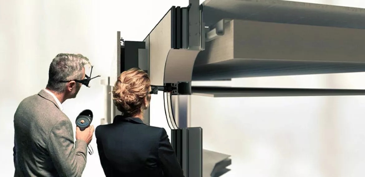 Architects observing modern glass façade building with Reynaers Aluminium systems.