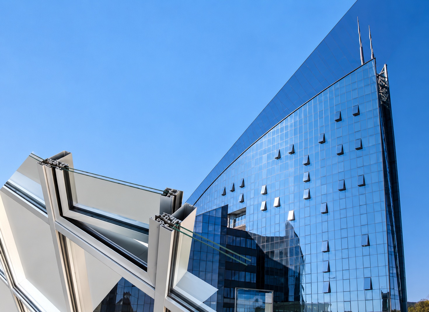 Modern glass curtain wall façade with aluminium framing, representing the ALUMIL SMARTIA M7 system.